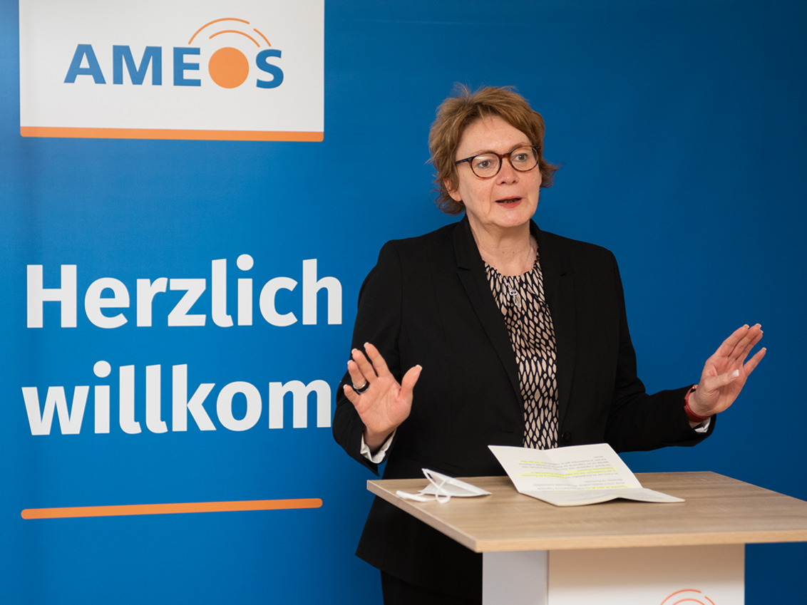 Ministerin Daniela Behrens an einem Rednerpult vor blauem Hintergrund mit AMEOS Logo